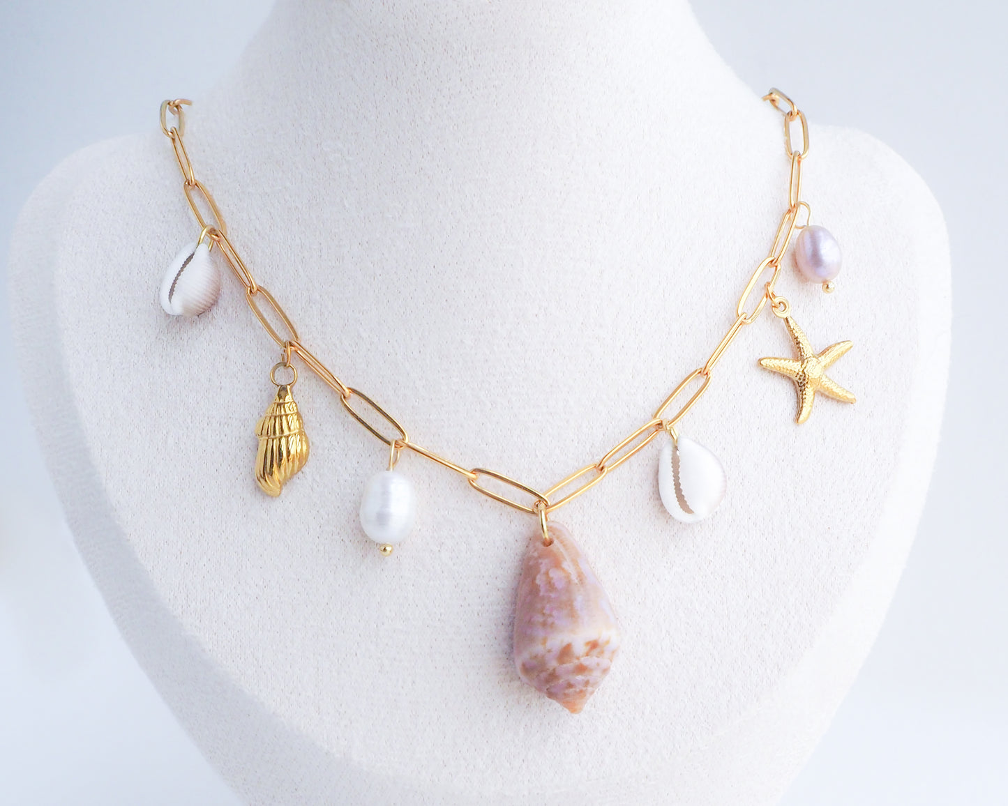 Gold Ocean Shell Charm Necklace on display cone and cowrie shells, freshwater pearls, starfish sea star and whale tail pendants. 