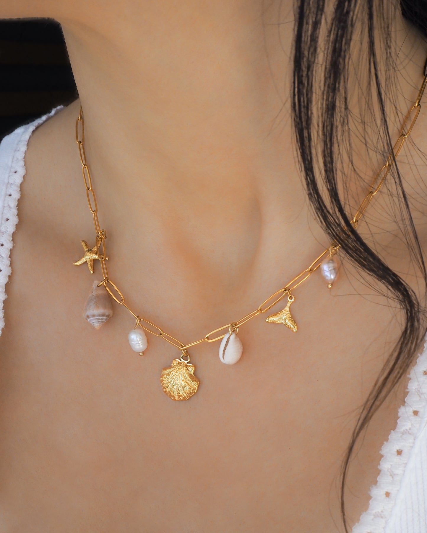 Gold Ocean Charm Necklace on neck model with freshwater pearls, cone shell, cowrie shell, starfish sea star and whale tail pendants. 