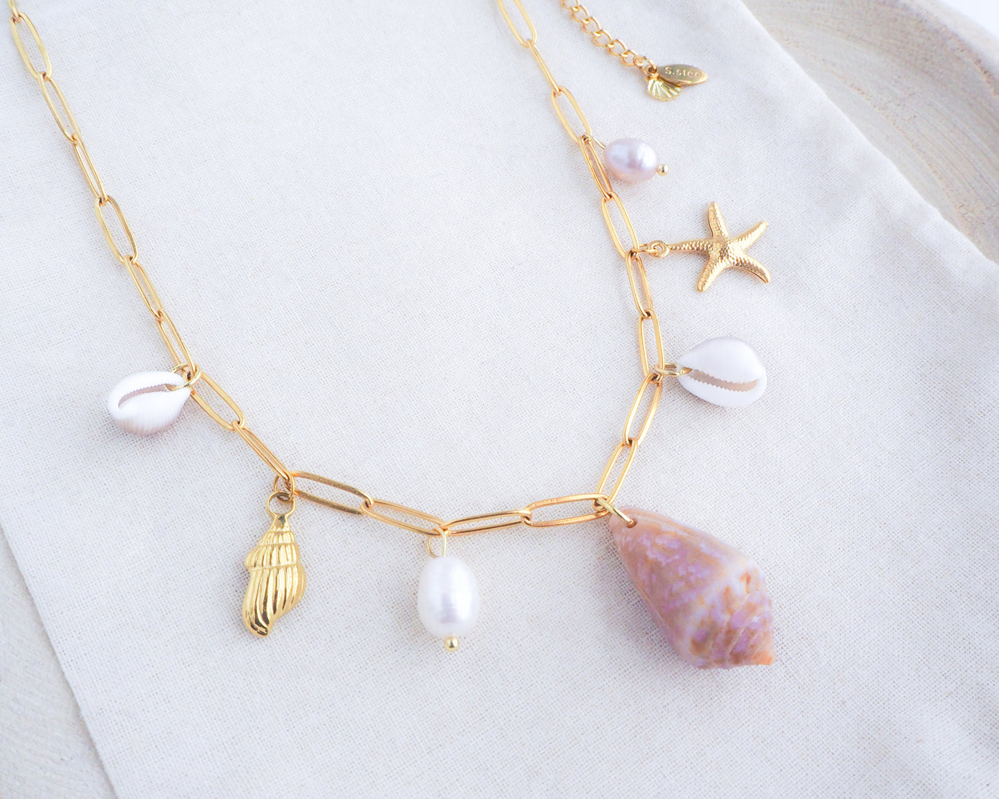 Gold Ocean Shell Charm Necklace on display, with cone and cowrie shells, freshwater pearls, starfish sea star shell pendants. 