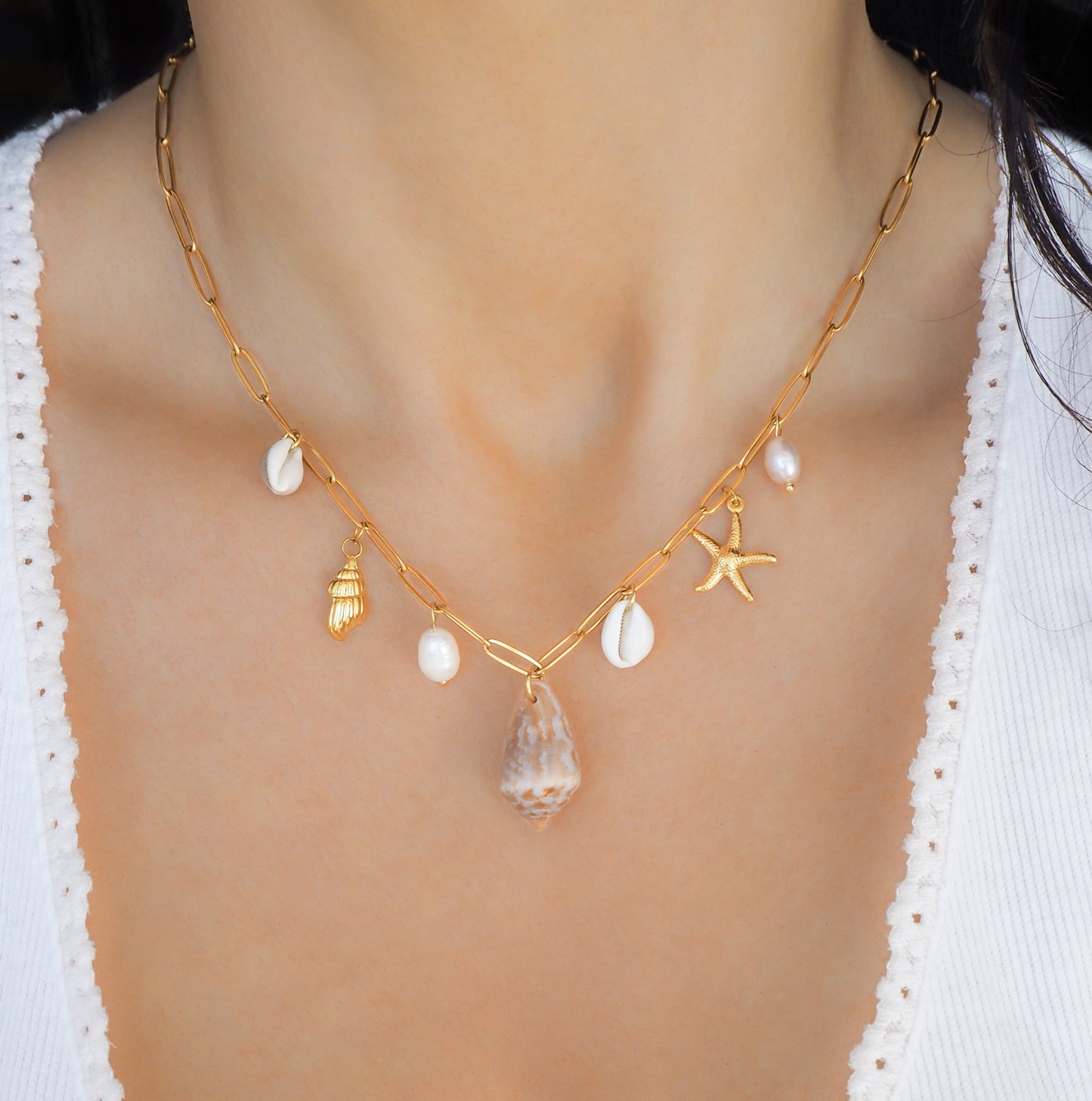 Gold Ocean Shell Charm Necklace on neck model, with cone and cowrie shells, freshwater pearls, starfish sea star shell pendants. 