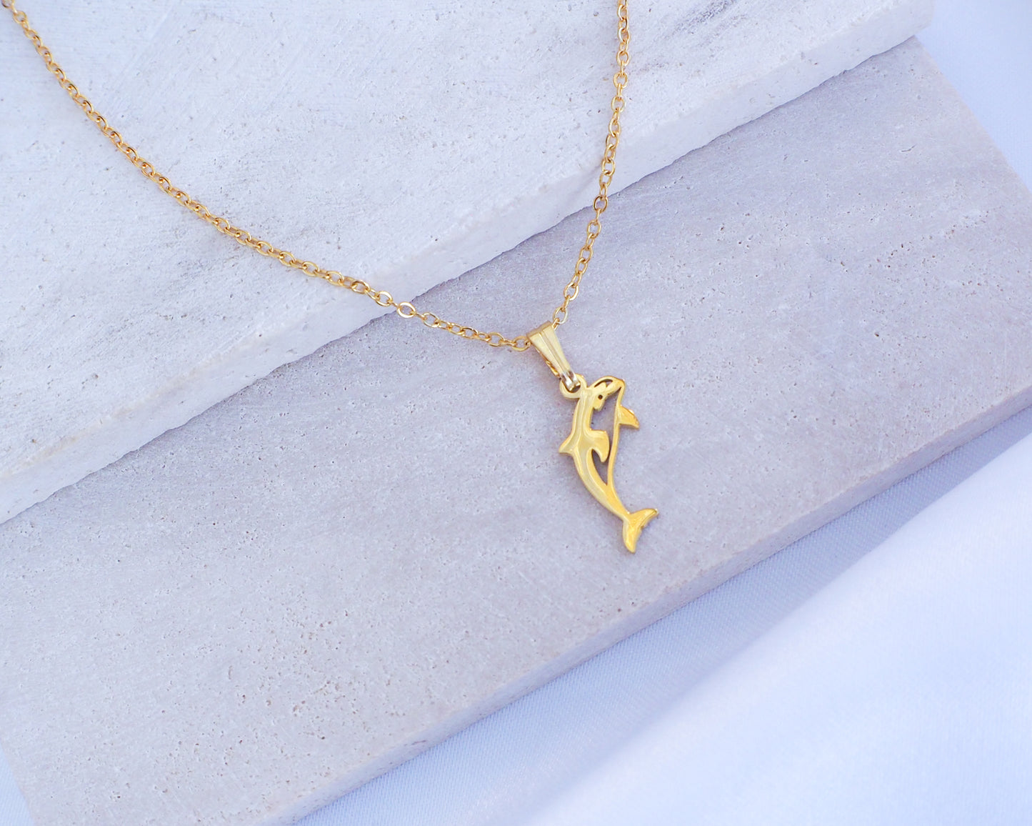 Gold Orca Killer Whale Necklace displayed on stone