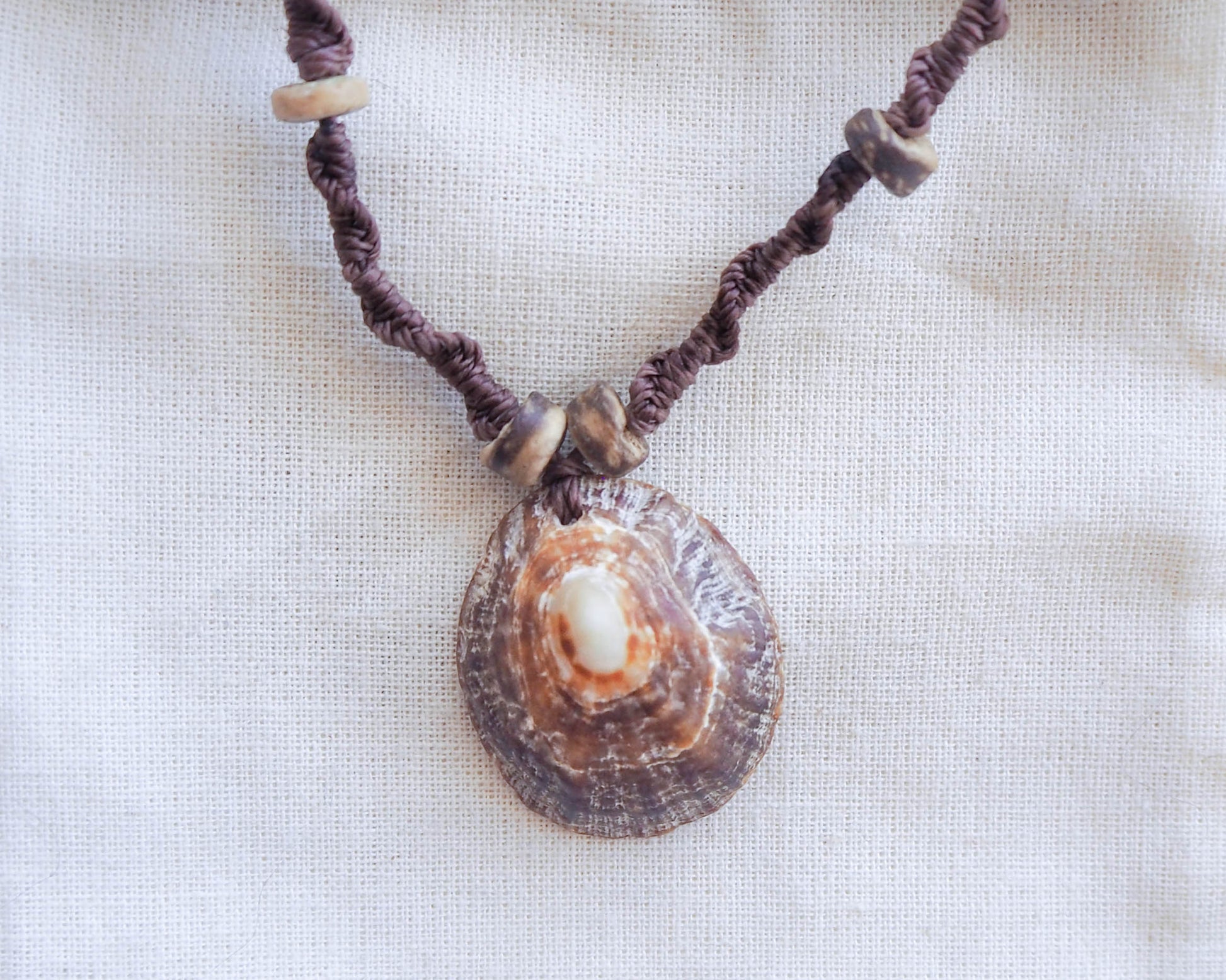 A detailed capture of the intricate braided pattern of the brown wax cord, showcasing the meticulous craftsmanship that went into creating this unique necklace. Wooden beads are skillfully woven into the braid, offering an alluring texture.