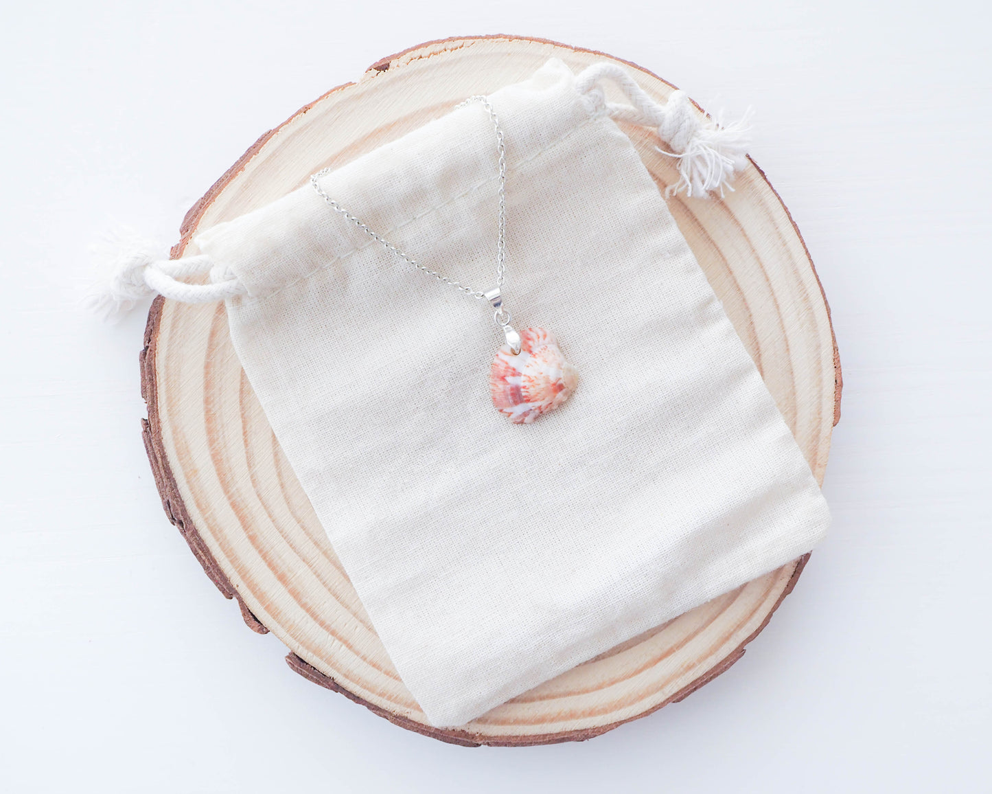 A close-up image of the Pink White Marmer Banded Venus Shell pendant, showcasing its vibrant fuchsia and ivory bands within a silver setting