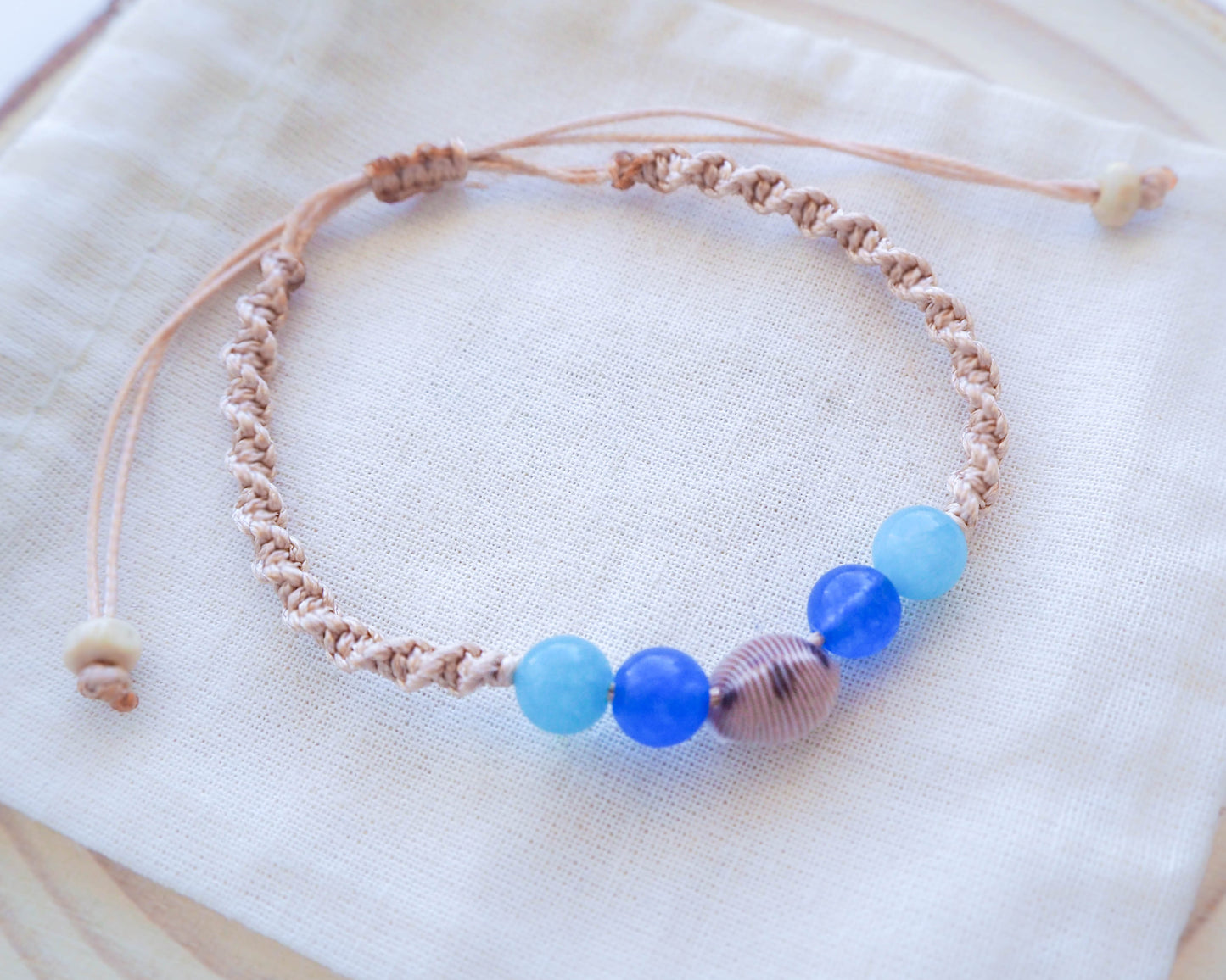 close-up of the aquamarine and blue agate beads, adding a touch of tranquility and harmony to the Cowrie Shell Bracelet.