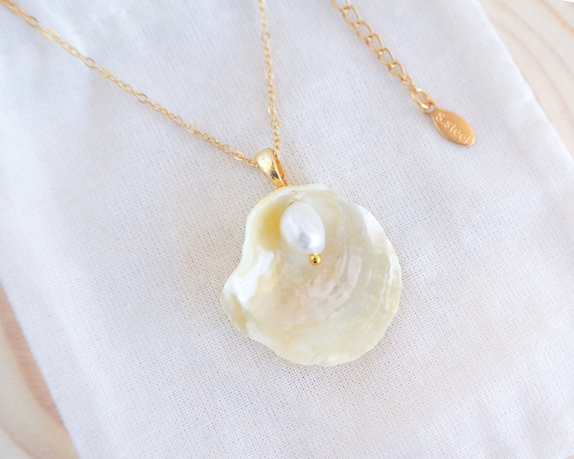 Yellow Jingle Shell Gold Necklace on display, Mother of Pearl Pendant