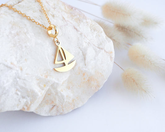 Gold Sailing Boat Necklace on stone