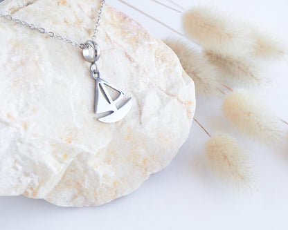 Silver Sailing Boat Necklace on stone