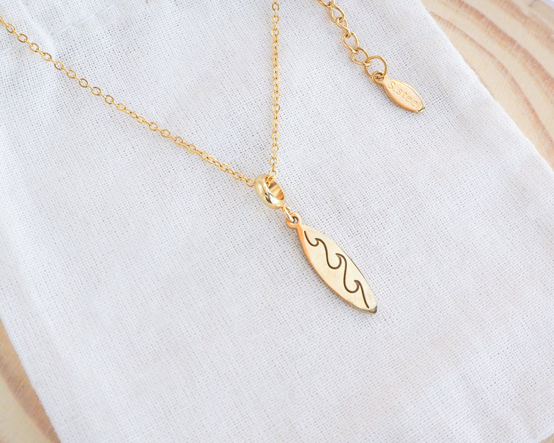 Gold Surfboard Necklace, Surf Girl Wave necklace, Waterproof beach jewelry on display