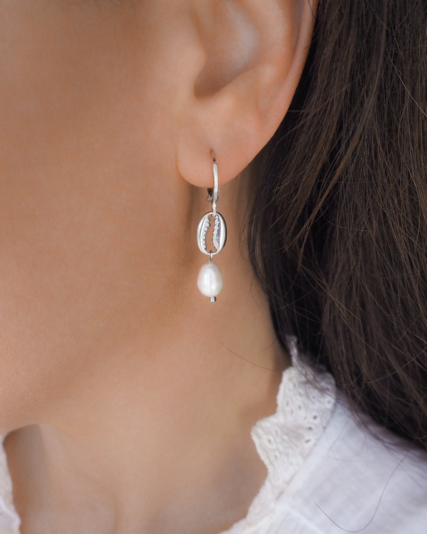 silver cowrie shell earrings with freshwater pearls in ear