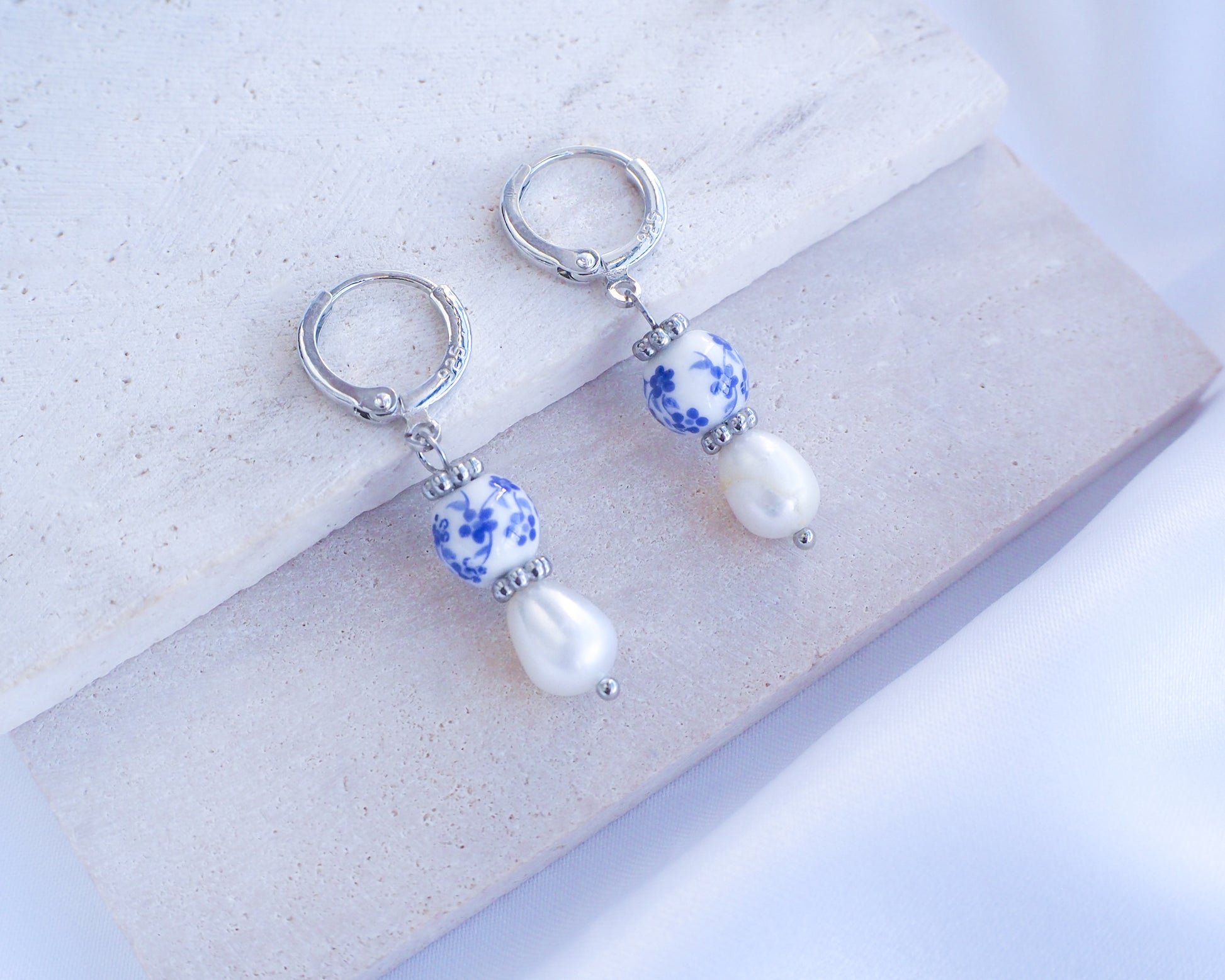 Model wearing Silver Portuguese Ceramic Pearl Earrings on stone, Azulejo Earrings from Portugal, Portuguese Tlles, Blue White Flower Porcelain Earrings